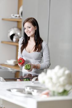 Beautiful young woman preparing food in her modern kitchen at home