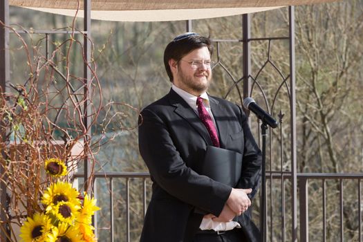 Smiling Caucasian Rabbi holding book by microphone