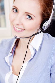 smiling young female callcenter agent with headset in office