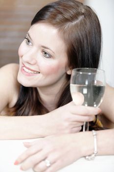 Attractive young woman lying on her sofa enjoying a glass of wine.