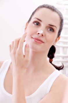 beautiful attractive woman applying cream on face skincare