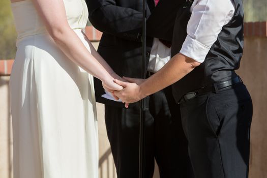 Women holding hands in wedding ceremony outdoors