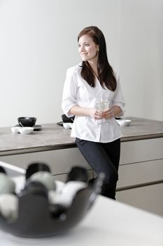 Beautiful young woman relaxing in her elegant white kitchen