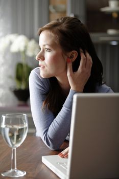 Attractive young woman using her laptop in the kitchen