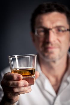 adult man holding an alcoholic drink thoughtful on black background