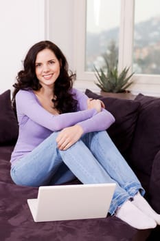 attractive young smiling woman on couch with notebook 