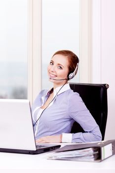 smiling young female callcenter agent with headset in office