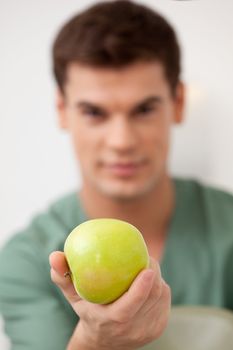 Dentist holding an apple out to the viewer, shallow depth of field, focus on apple