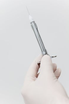 Close-up of human hand holding needle against white background