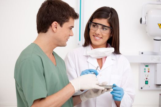 Dental team in office holding sterile tools with x-ray equipment in background