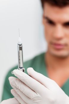 Close-up of young doctor wearing rubber gloves and holding injection