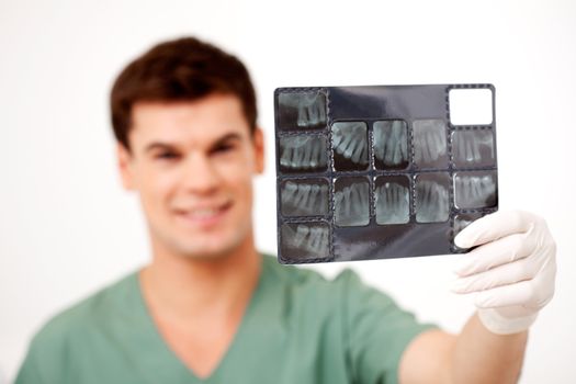 Young male dentist holding an x-ray, shallow depth of field - focus on x-ray