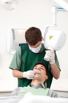 Dentist preparing x-ray machine on young male patient