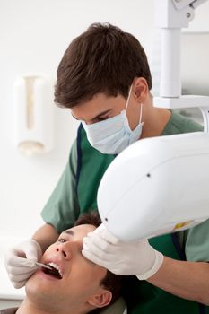 Young man dentist giving an x-ray to a patient