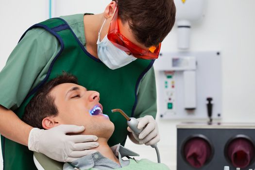 Dentist using UV light on patients teeth