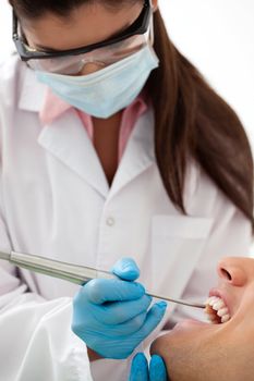 Female dentist examining man's teeth in dental office