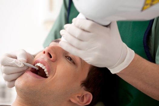 Dentist preparing to take an x-ray of a young adult's teeth