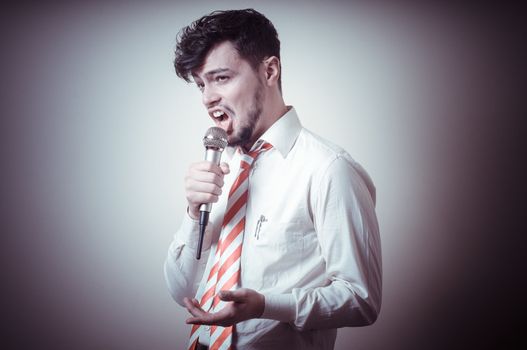 funny stylish businessman singing on gray background
