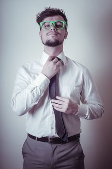 sexy stylish businessman adjusting tie on gray background