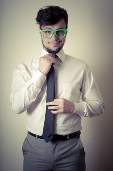 sexy stylish businessman adjusting tie on gray background