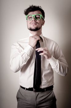 sexy stylish businessman adjusting tie on gray background