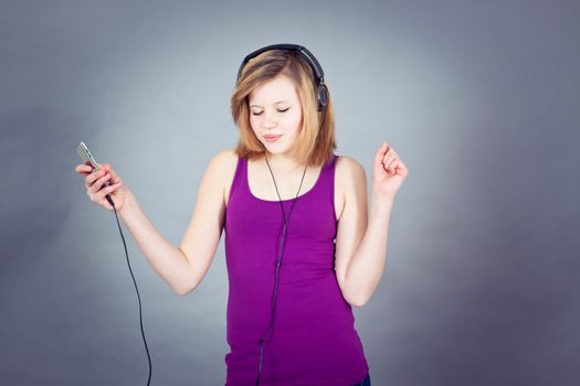 young smiling teenager girl dancing with mp3 player and earphones listening to music
