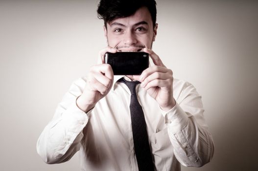 businessman taking photo with telephone on gray background