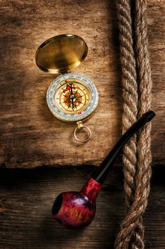 Compass and a pipe with a rope on the background of the old board