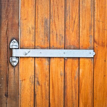 A modern metal hinge on a wooden door