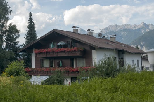 traditonal house in austria with red geranium flowers on the balcony