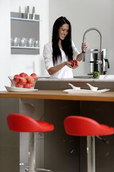 Beautiful young woman preparing food in her modern kitchen at home