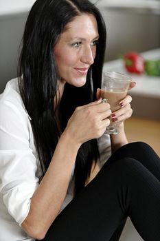 Attractive young woman taking a coffee break in her kitchen