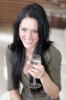 Attractive young woman relaxing on her sofa at home with a glass of white wine.