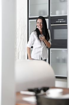 Beautiful young woman relaxing in her elegant white kitchen