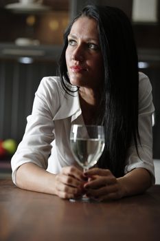 Attractive young woman enjoying a glass of wine in her kitchen.