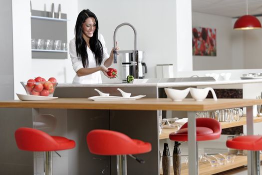 Beautiful young woman preparing food in her modern kitchen at home