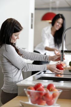 Two attractive friends preparing food in their kitchen at home.