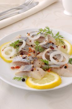 Slices of salted herring fillet with onion, lemon and spices