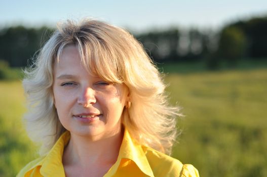 Portrait of beautiful girl in green field in summer time