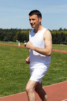 young man running on a track in a park