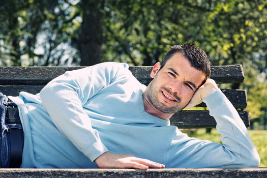 relaxed handsome man on a bench in a park