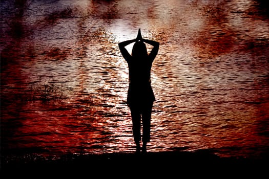A silhouette of a Hindu woman praying on the banks of the holy river Ganges in India.