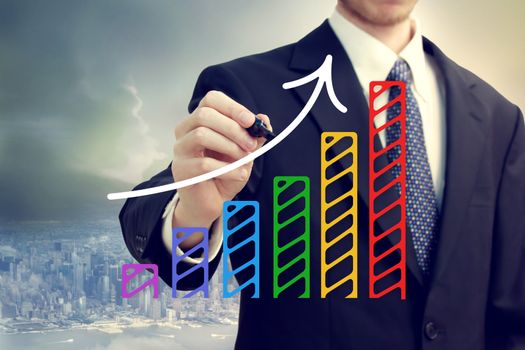 Businessman drawing a rising arrow over a bar graph above the city