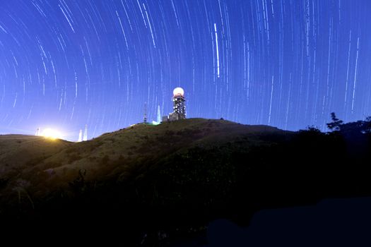 Mountain silhouette with a blue background at night with startrail 