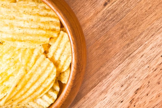 bowl of potato crisps on a wooden table