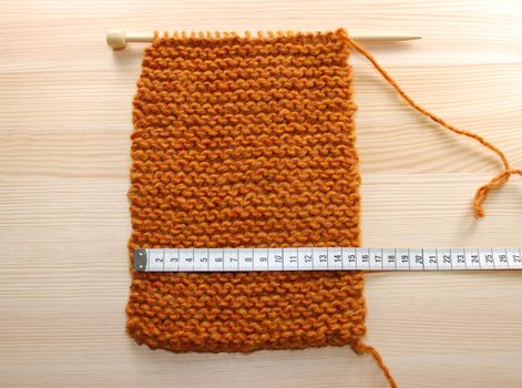 A length of knitting in garter stitch being measured in centimetres