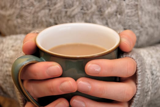 Two hands keeping warm, holding a hot cup of tea or coffee