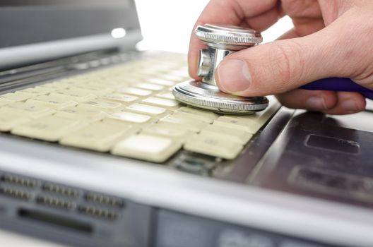 Serviceman checking and old and dirty laptop with a stethoscope. Shallow dof.