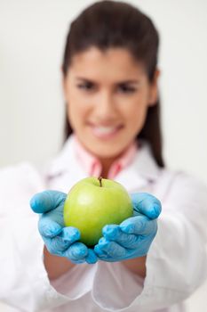 Closeup of female doctor holding a green apple