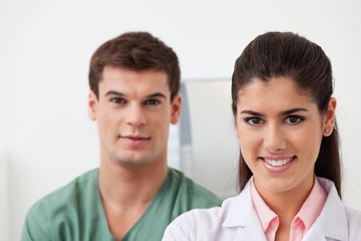 Portrait of pretty female doctor smiling with colleague standing behind